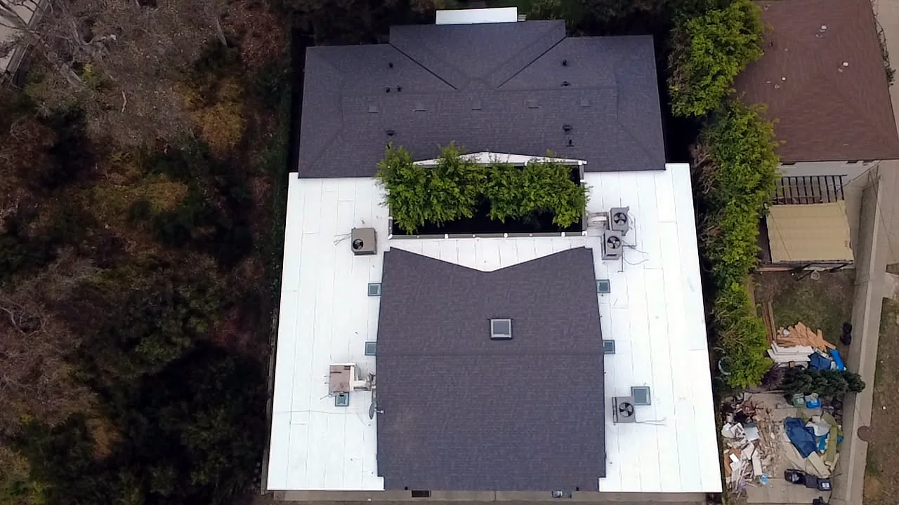 Top-down drone view of shingle and white flat roof sections around a courtyard in West Los Angeles