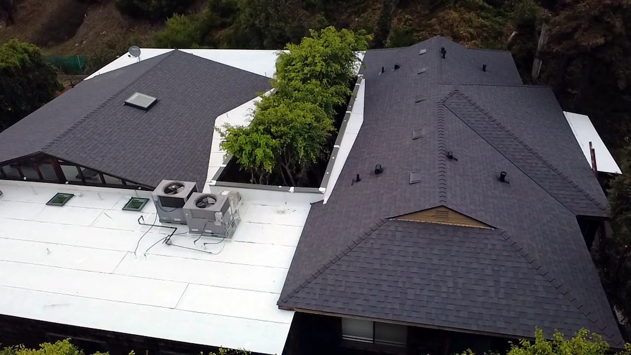 Hip and valley shingle details next to a white flat roof with HVAC units in West Los Angeles